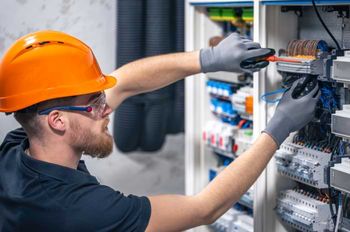 Man wearing orange hardhat working on electrical equipment