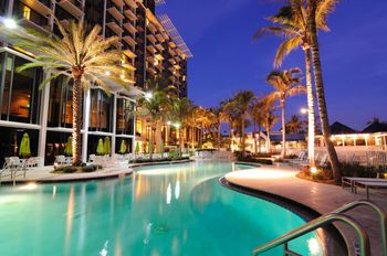 A hotel pool at night with palm trees and lights