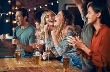 Group of friends drinking in bar and cheering