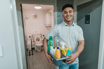 smiling man holding tray of cleaning supplies