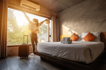 Woman admiring sunny view from hotel room with arms outstretched