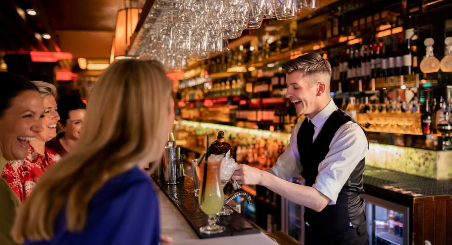 smiling bartender serving drinks in upscale bar