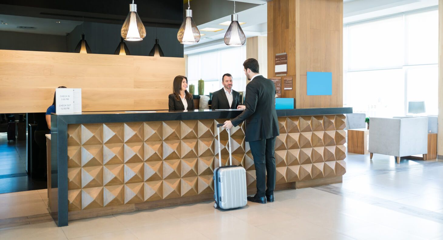 A man with a suitcase at the front desk of a hotel