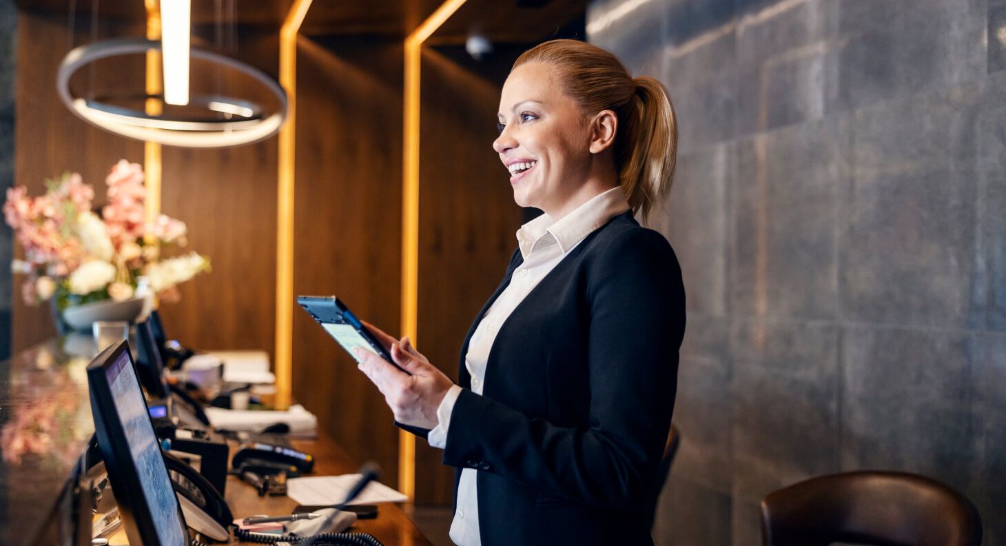 Woman at hotel front desk greeting a guest