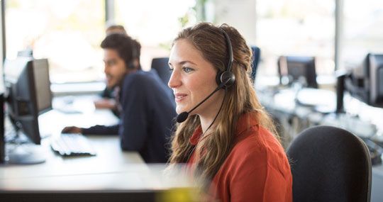 Smiling woman wearing a headset answering call at call center