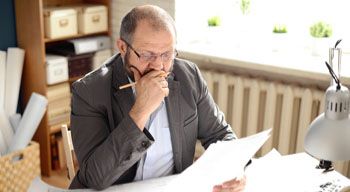 businessman in suit sitting at desk reading paperwork