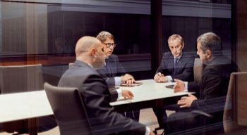 businessmen sitting around table in meeting room having serious discussion