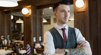 man in barber shop standing crossed armed