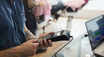 man in salon holding a card reader paying for services