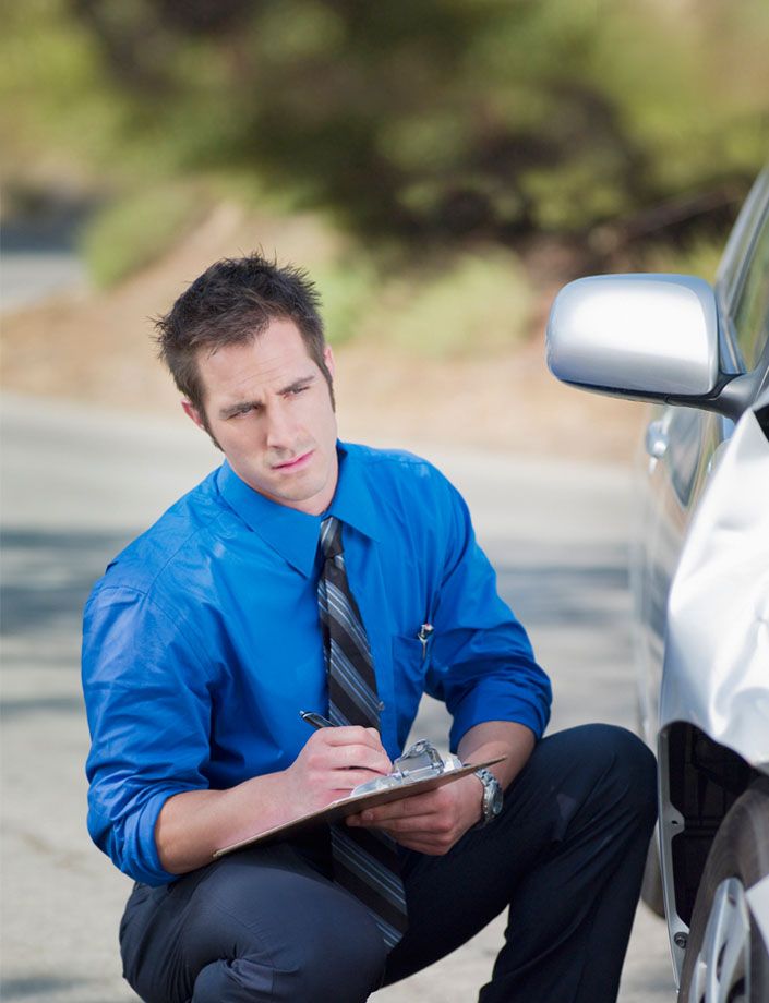 insurance agent inspecting damaged car