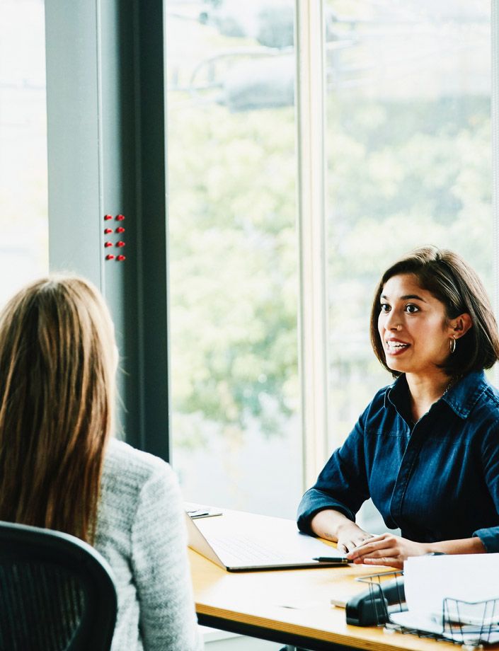 women in office having discussion seated at a desk