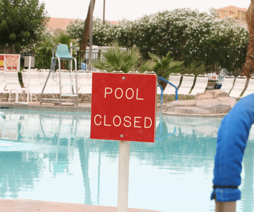 Red sign that says pool closed next to hotel pool