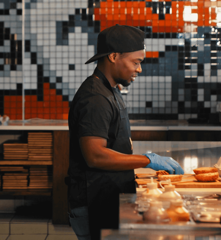 Side view of chef assembling sandwiches in commercial kitchen