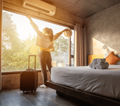 Woman with outstretched arms admiring sunrise view of hotel room