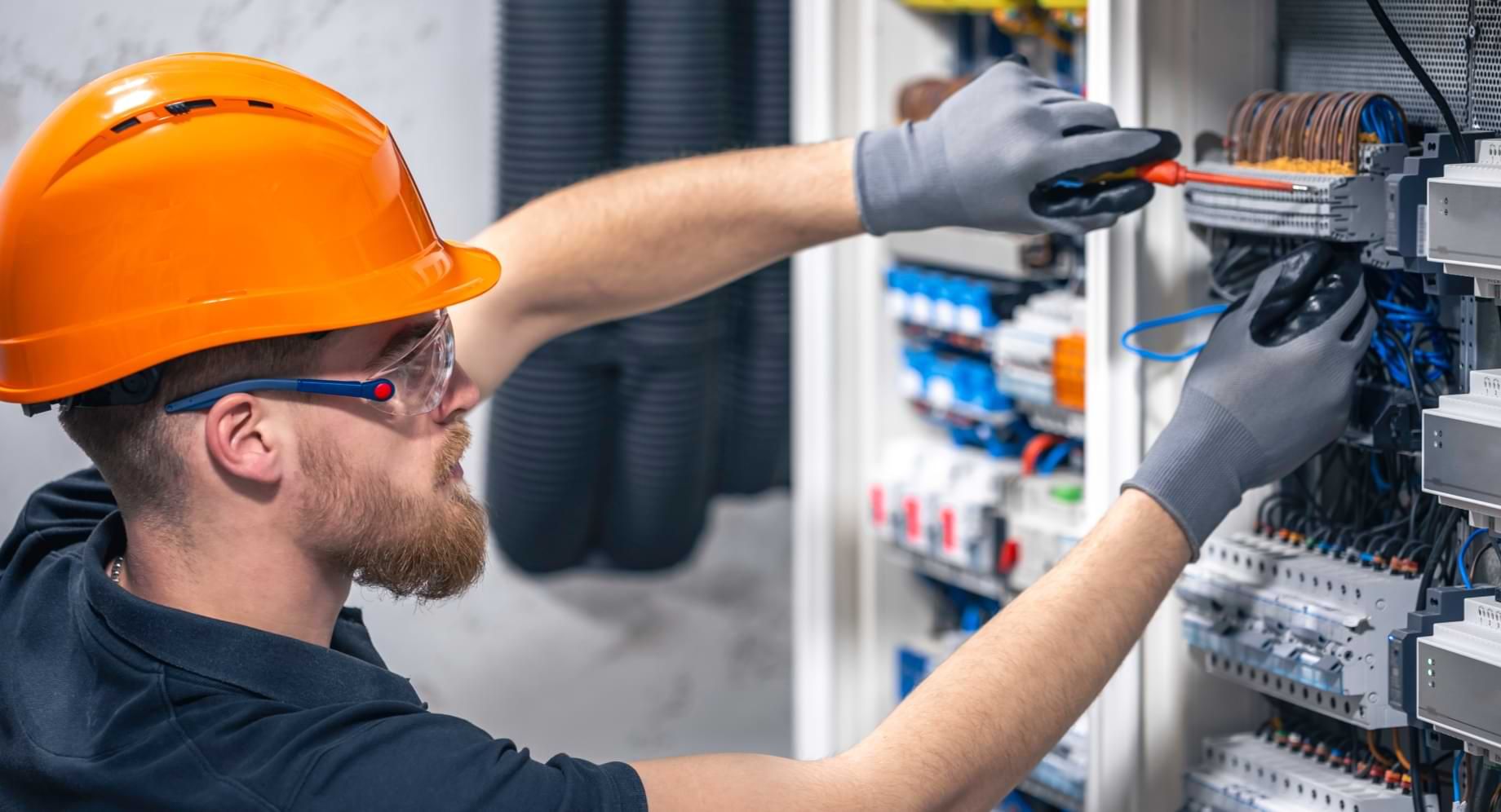 Man wearing orange hardhat working on electrical equipment