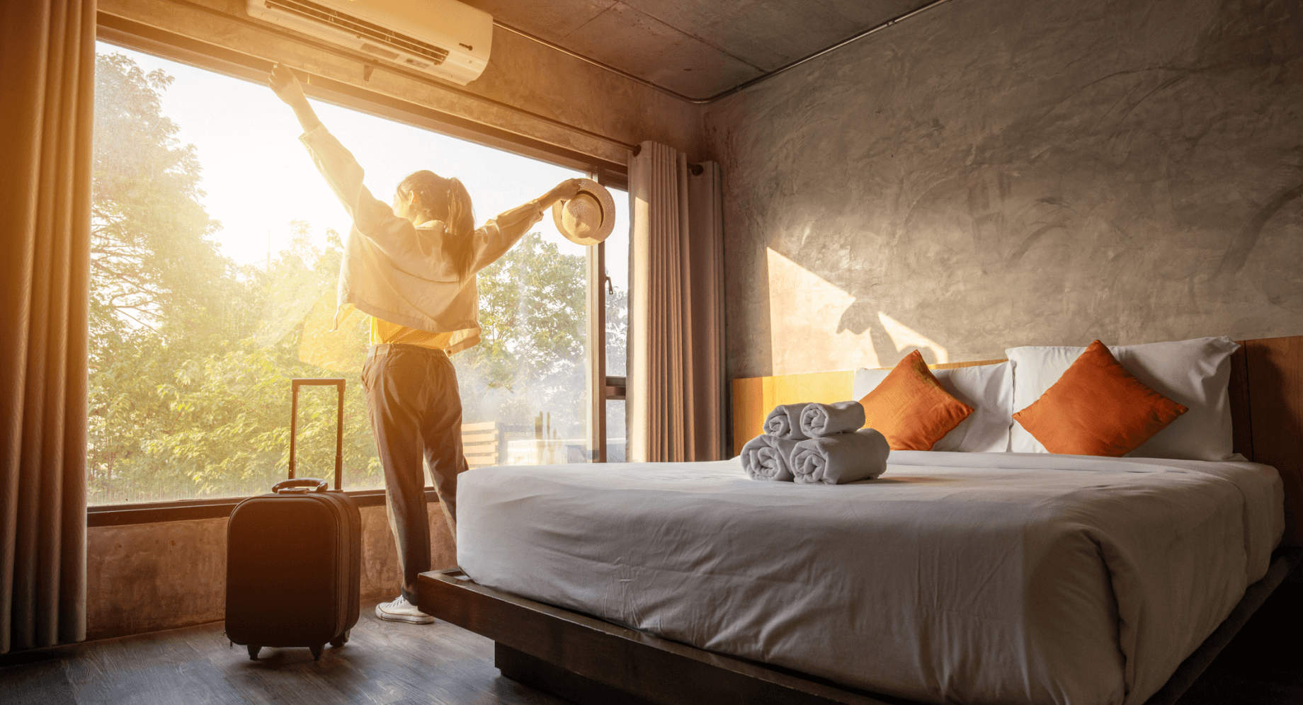 Woman admiring sunny view from hotel room with arms outstretched
