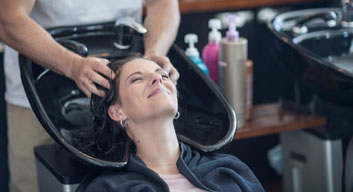 Woman in salon getting hair washed and smiling