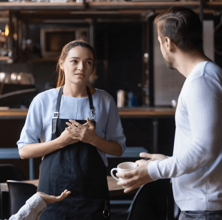 Worried worker wearing an apron talking to her manager