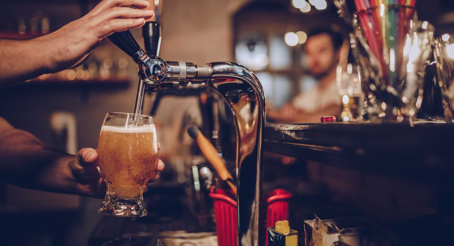 Man in pub pouring beer from tap